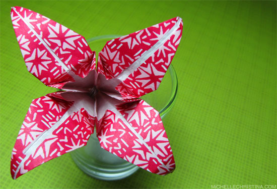 origami red paper flower on green background